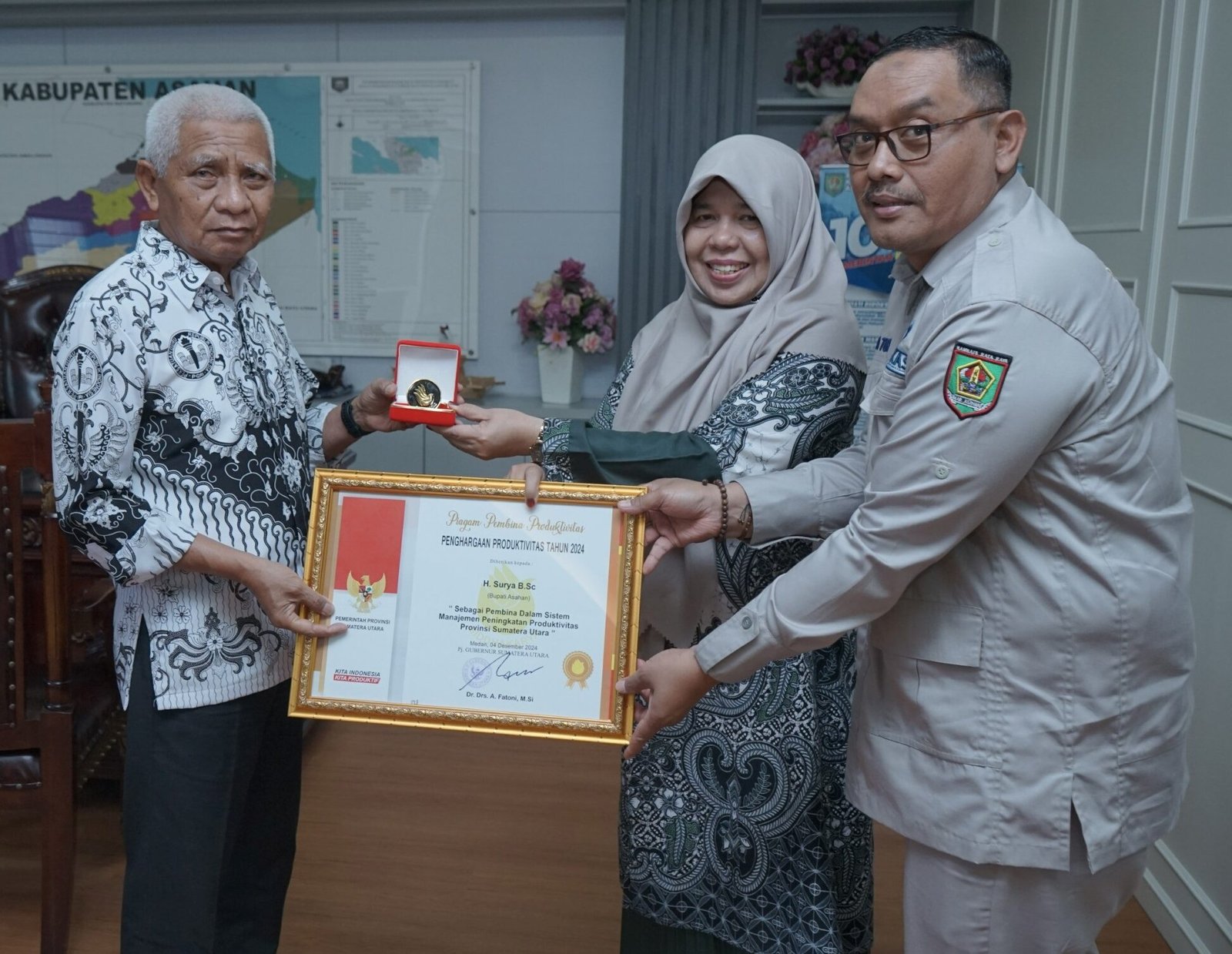 Kepala Dinas Ketenagakerjaan Kabupaten Asahan serahkan Lencana dan Penghargaan yang diperoleh kepada Bupati Asahan Surya